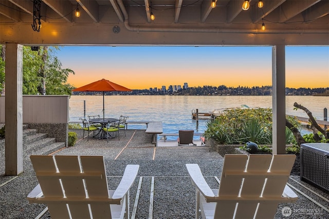 patio terrace at dusk with central AC, a dock, and a water view