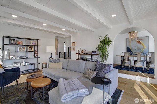 living room with beamed ceiling, arched walkways, an inviting chandelier, recessed lighting, and wood finished floors
