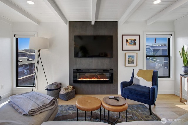 living area featuring recessed lighting, wood finished floors, a large fireplace, baseboards, and beam ceiling