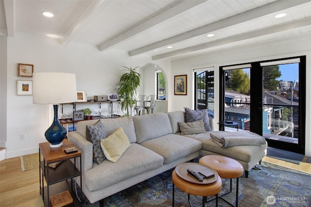 living area with recessed lighting, wood finished floors, arched walkways, beamed ceiling, and baseboards