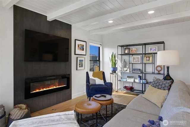 living area featuring a fireplace, beam ceiling, wood finished floors, and baseboards