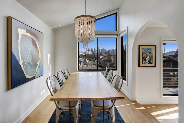 dining space with a wealth of natural light, wood finished floors, and an inviting chandelier