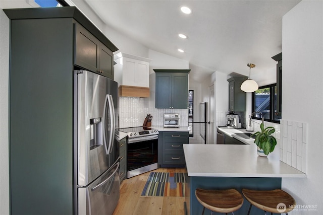 kitchen with tasteful backsplash, a sink, appliances with stainless steel finishes, light wood-style floors, and a peninsula