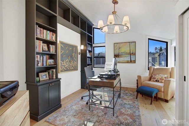 home office featuring wood finished floors, plenty of natural light, a notable chandelier, and baseboards