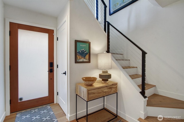 entryway featuring stairs, light wood-style flooring, and baseboards