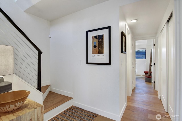 hallway featuring stairway, light wood-type flooring, and baseboards