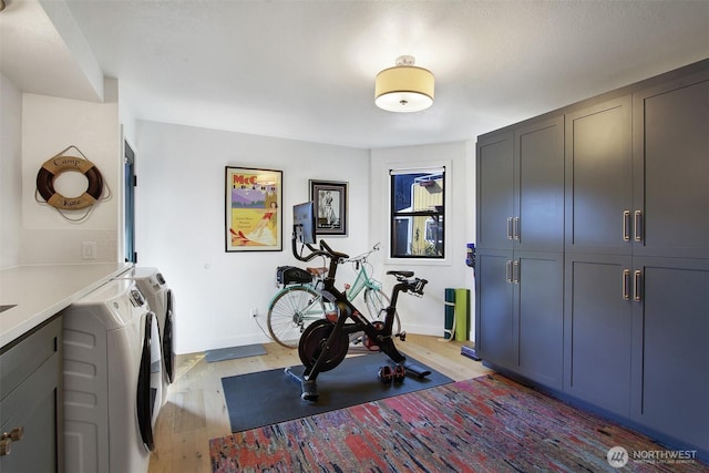 exercise room featuring light wood finished floors, separate washer and dryer, and baseboards
