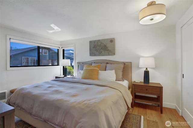bedroom featuring wood finished floors, visible vents, and baseboards