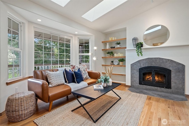 sitting room featuring recessed lighting, wood finished floors, a tile fireplace, and lofted ceiling with skylight