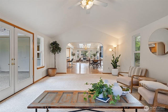 living room featuring arched walkways, vaulted ceiling, baseboards, ceiling fan with notable chandelier, and carpet floors
