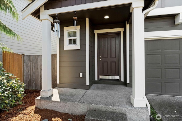 view of exterior entry featuring fence and a porch