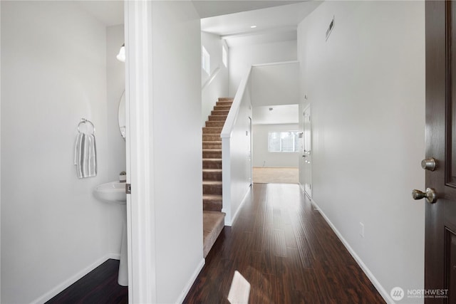 hall with stairs, baseboards, visible vents, and wood finished floors