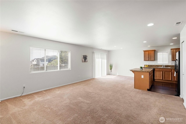 unfurnished living room featuring a sink, carpet floors, recessed lighting, and visible vents