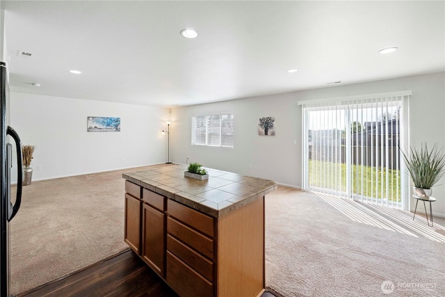 kitchen featuring freestanding refrigerator, dark carpet, open floor plan, recessed lighting, and tile countertops