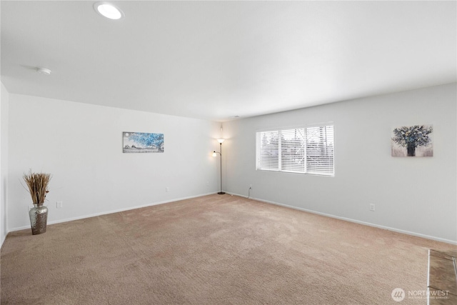 spare room featuring baseboards and light carpet