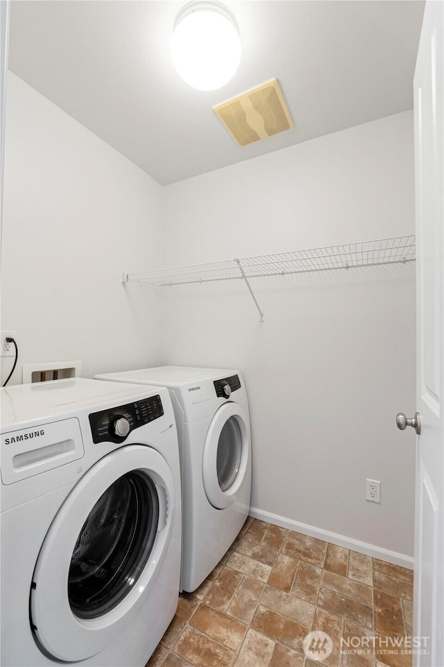 washroom with laundry area, stone finish flooring, visible vents, baseboards, and separate washer and dryer