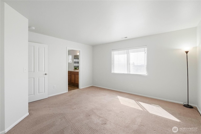 unfurnished bedroom with baseboards, visible vents, light carpet, and ensuite bath