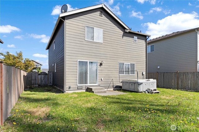 rear view of house featuring a lawn, a fenced backyard, a hot tub, and entry steps