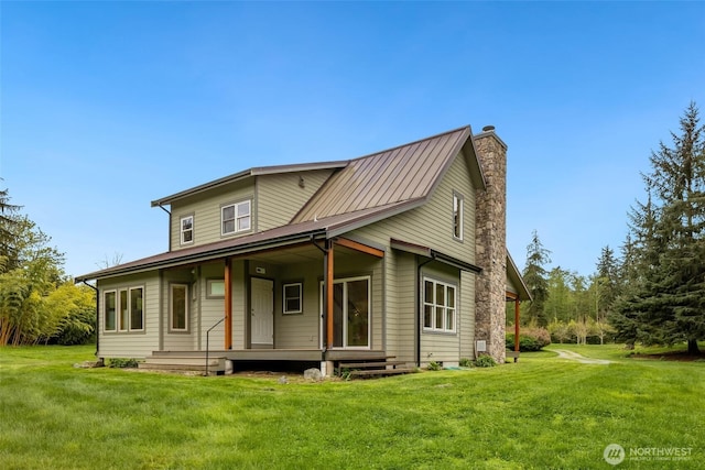 view of front of home with metal roof, a chimney, a front yard, and covered porch