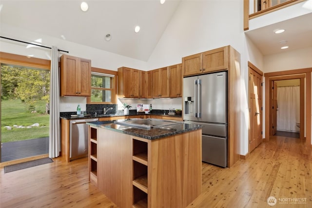 kitchen with light wood finished floors, stainless steel appliances, a kitchen island, open shelves, and high vaulted ceiling