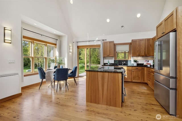 kitchen featuring dark stone countertops, high end refrigerator, light wood-style floors, and a kitchen island