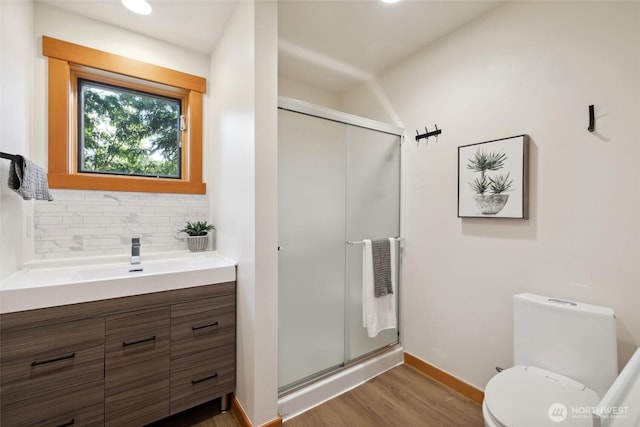 full bathroom featuring baseboards, a shower stall, wood finished floors, and backsplash