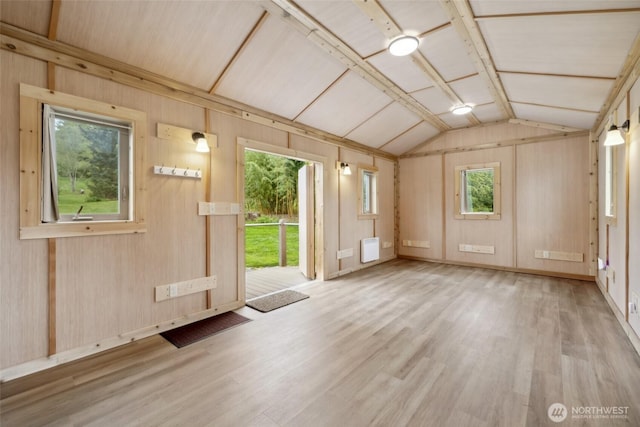 spare room featuring lofted ceiling, wood finished floors, and wood walls