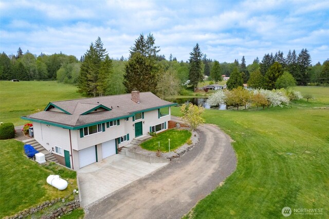 view of front facade featuring an attached garage, a chimney, concrete driveway, and a front yard