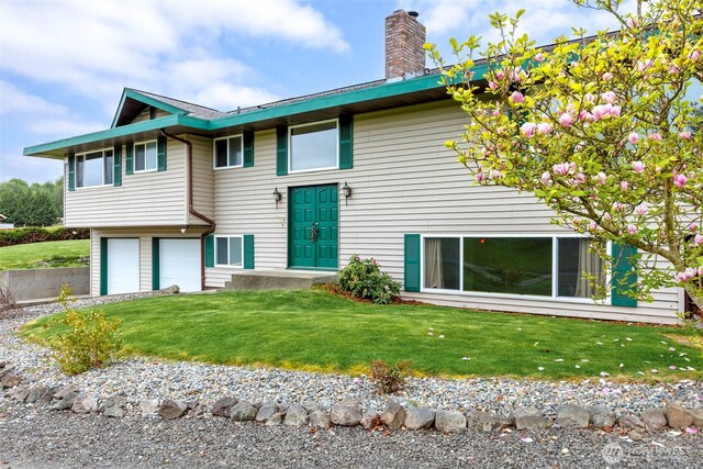 exterior space with a garage, a front lawn, driveway, and a chimney