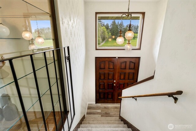 foyer with stairway, plenty of natural light, and a notable chandelier