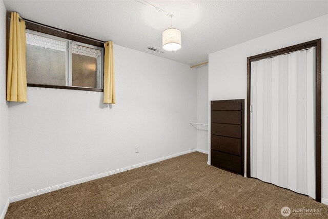 unfurnished bedroom featuring baseboards, carpet flooring, and visible vents