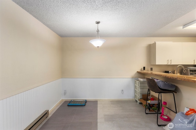 2534 S 317th St Unit 103, Federal Way, WA 98003 - dining space with baseboard heating, wainscoting, and a textured ceiling