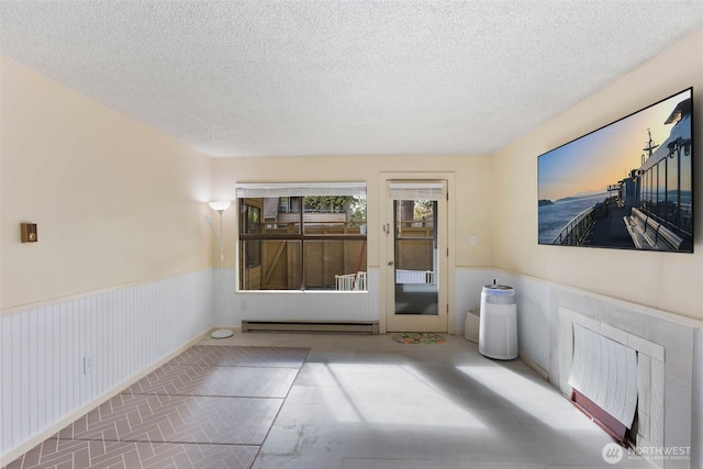 2534 S 317th St Unit 103, Federal Way, WA 98003 - spare room featuring brick floor, a textured ceiling, a wainscoted wall, and a baseboard heating unit