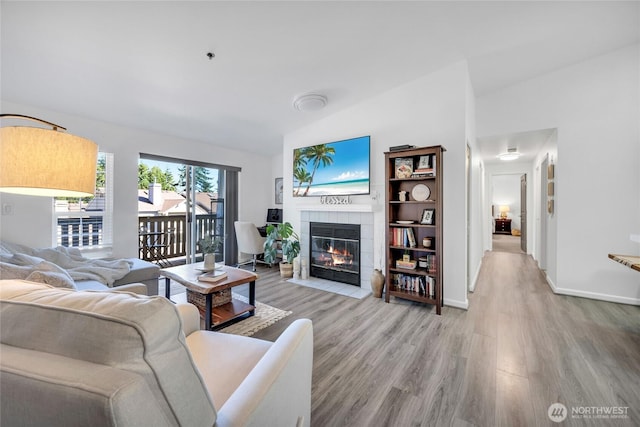 215 100th St SW Unit B307, Everett, WA 98204 - living room featuring lofted ceiling, a tiled fireplace, light wood-style floors, and baseboards