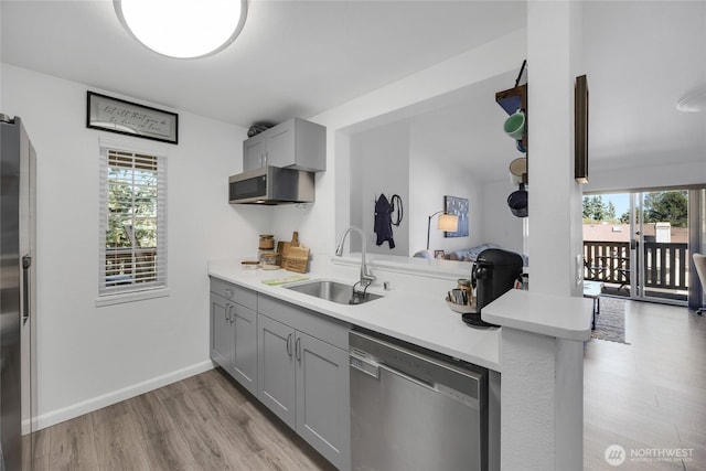 215 100th St SW Unit B307, Everett, WA 98204 - kitchen featuring appliances with stainless steel finishes, a sink, gray cabinetry, light wood-style flooring, and a peninsula