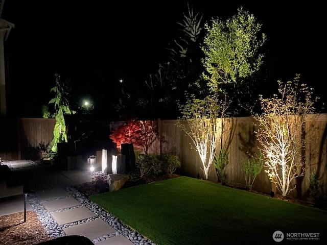 yard at night with a fenced backyard