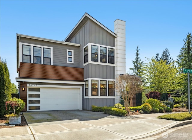 contemporary house with concrete driveway, a garage, board and batten siding, and a chimney