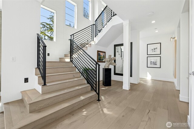 stairs featuring baseboards, decorative columns, wood finished floors, and recessed lighting