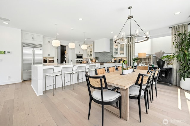 dining room with baseboards, light wood-type flooring, a notable chandelier, and recessed lighting