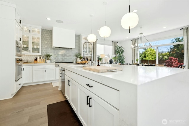 kitchen with white cabinetry, stainless steel appliances, light countertops, and a sink