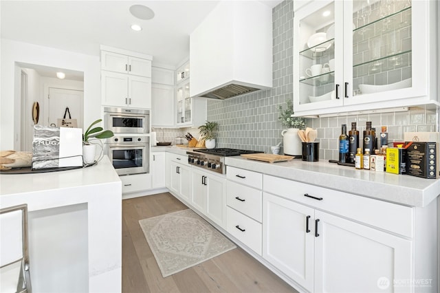 kitchen featuring light wood-style flooring, custom exhaust hood, light countertops, and stainless steel gas cooktop