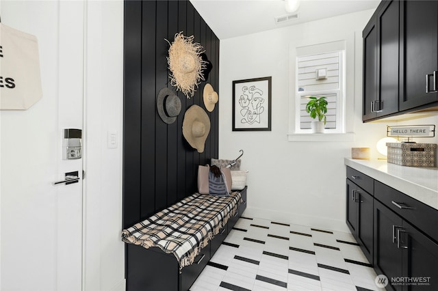 mudroom with baseboards, visible vents, and light floors