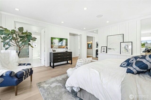 bedroom featuring ornamental molding, recessed lighting, light wood-style flooring, and a decorative wall