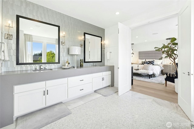 ensuite bathroom featuring double vanity, a sink, wood finished floors, and ensuite bathroom