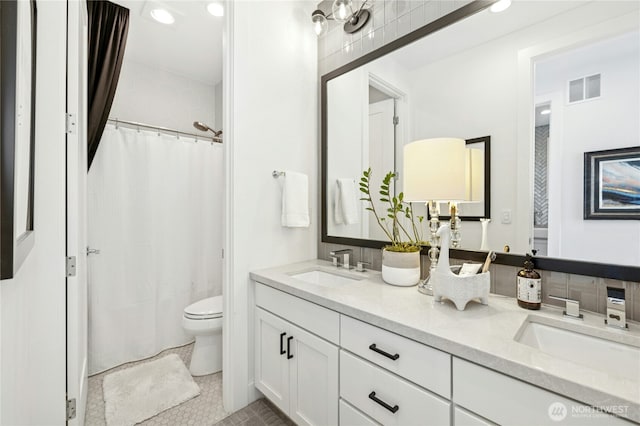 full bath with a sink, double vanity, visible vents, toilet, and tile patterned floors