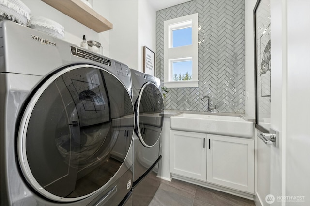 washroom featuring washing machine and clothes dryer, cabinet space, and a sink