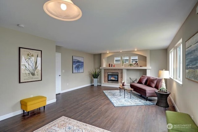 living area featuring baseboards, dark wood-style floors, and a tile fireplace