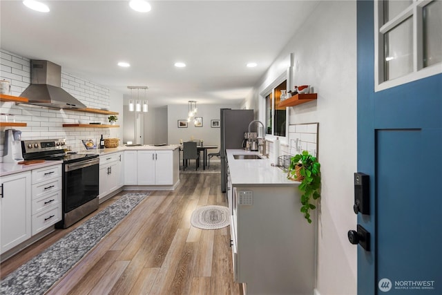 kitchen with open shelves, wall chimney range hood, white cabinetry, backsplash, and stainless steel range with electric cooktop