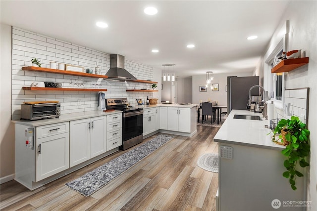 kitchen with open shelves, wall chimney range hood, tasteful backsplash, a sink, and stainless steel appliances