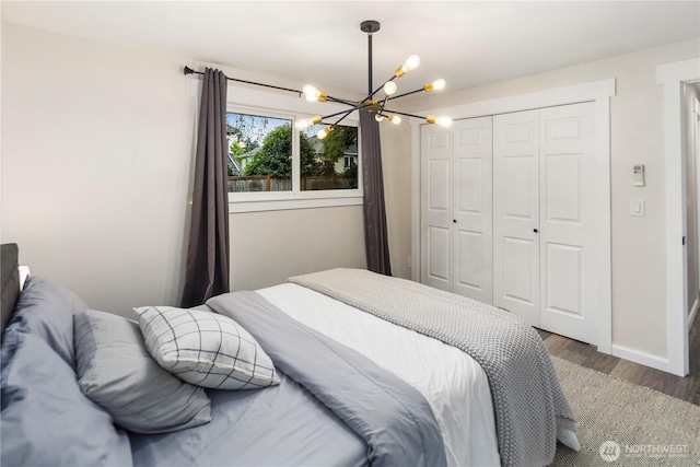 bedroom with baseboards, a closet, wood finished floors, and a chandelier